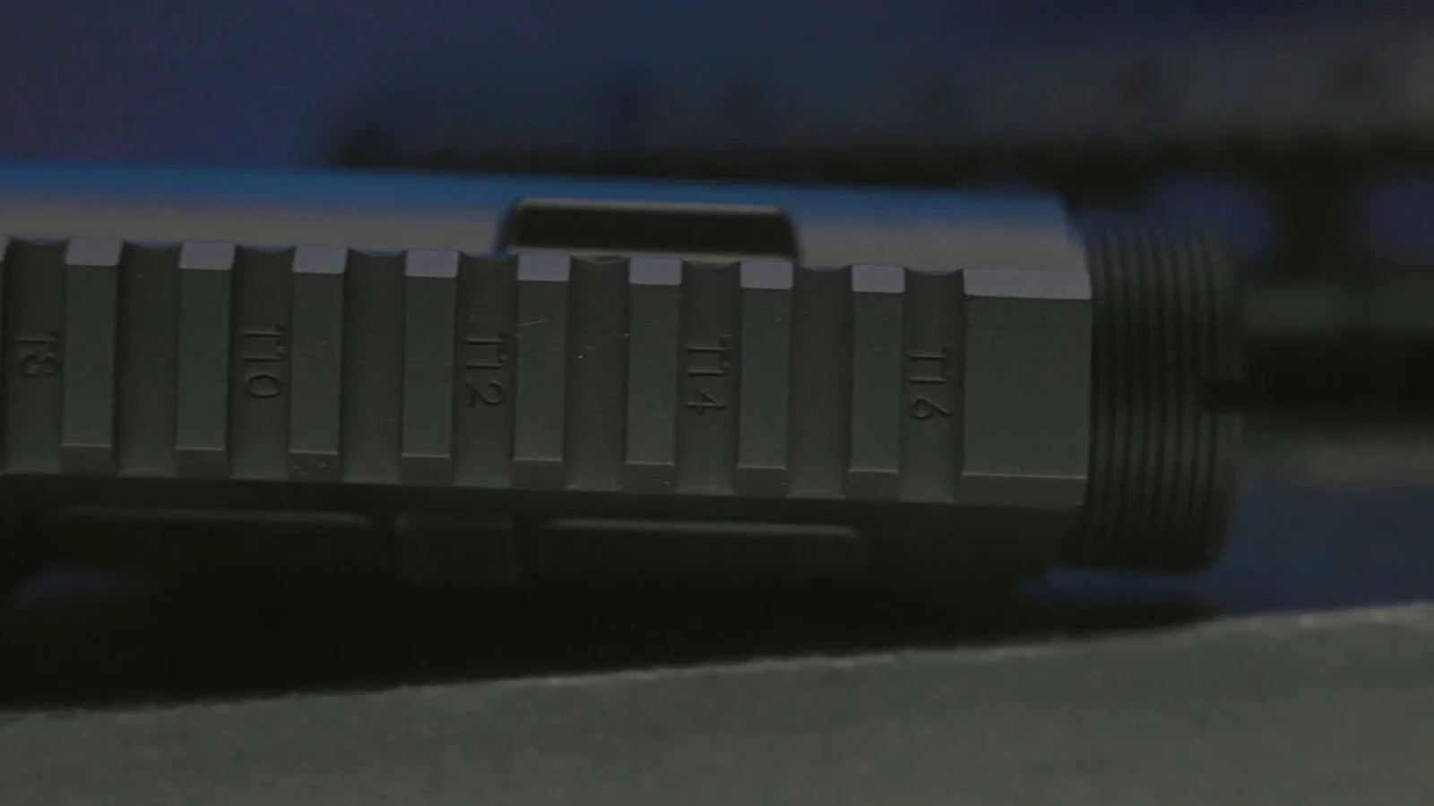 Macro shot of the Sabre-10 upper receiver top rail showing engraved T8, T10, T12, T14, and T16 position numbers next to the threaded barrel nut interface