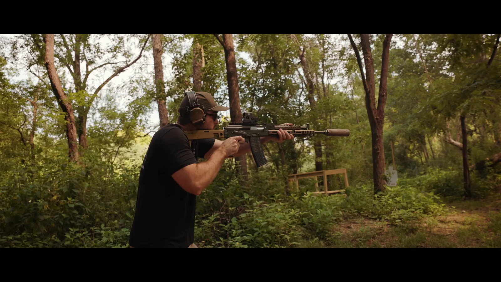 Shooter firing the suppressed PSA Sabre 5.56 AK at an outdoor range