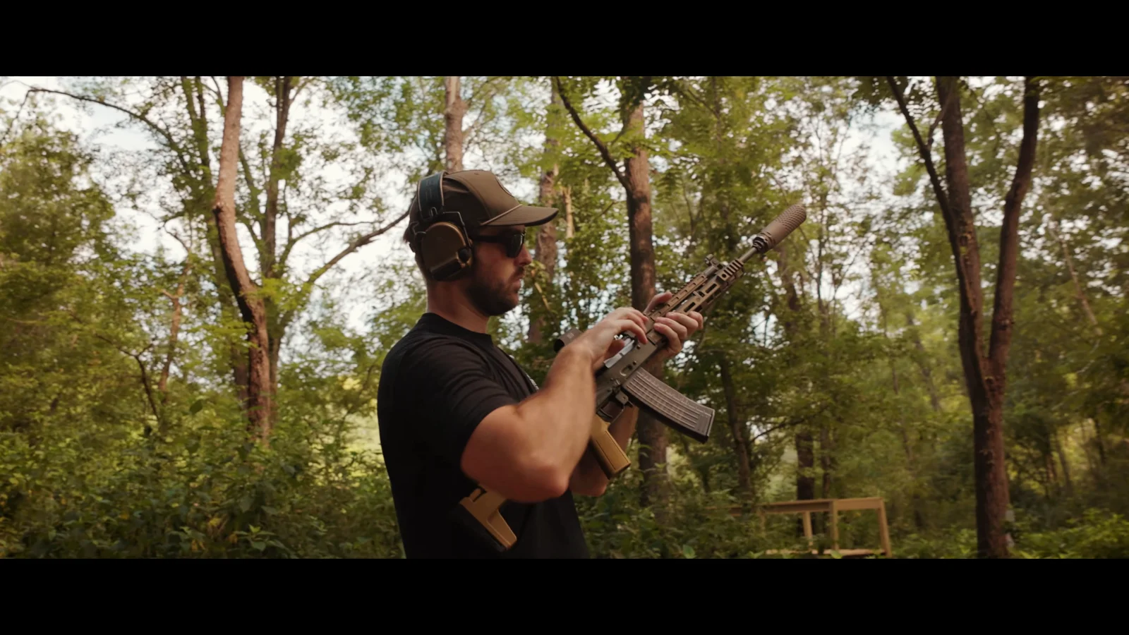 Shooter holding the suppressed PSA Sabre 5.56 AK with its translucent WBP 5.56 magazine and B5 side-folding stock visible