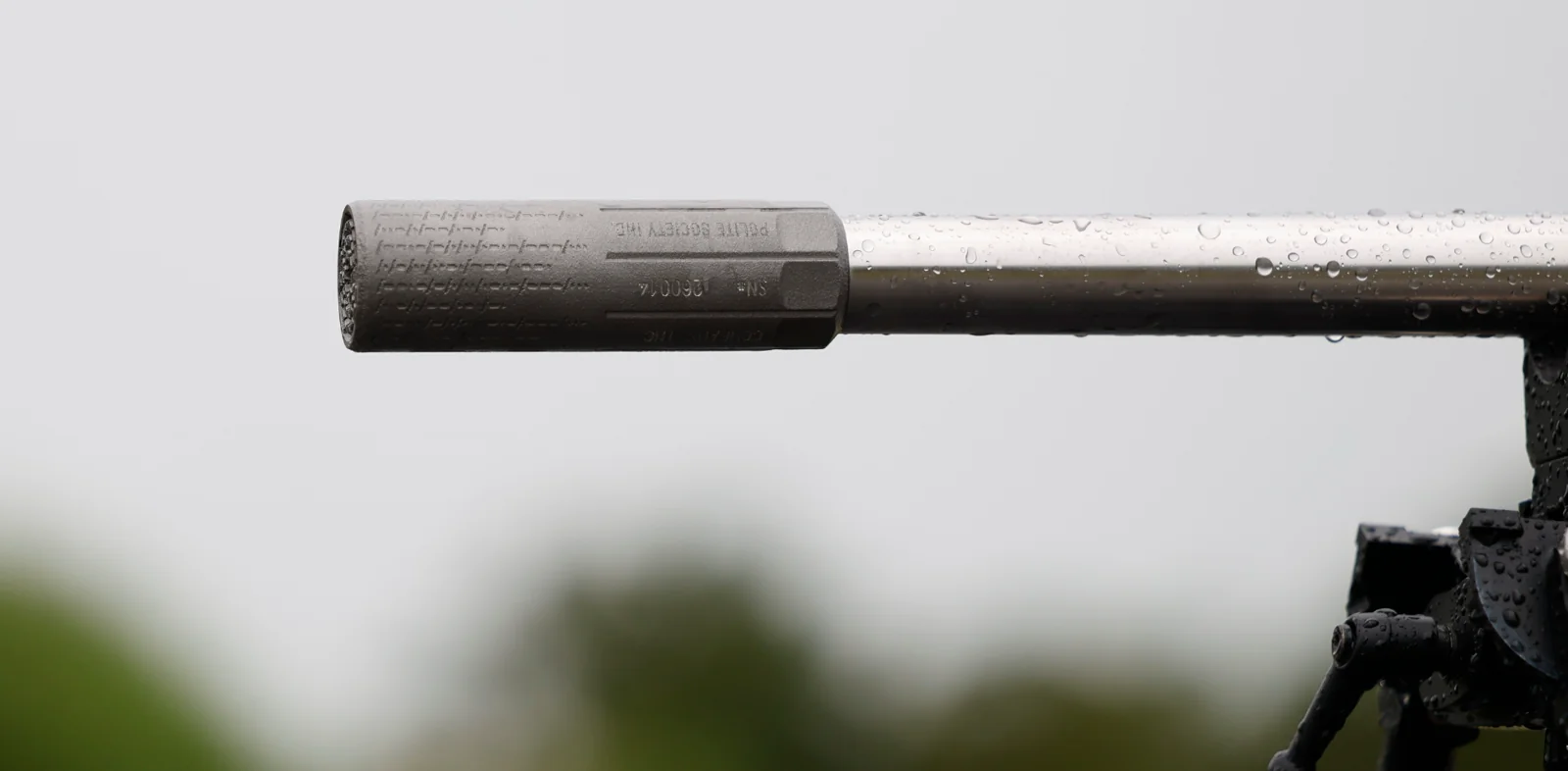 Polite Society Temperance .22 titanium suppressor on a stainless barrel, showing POLITE SOCIETY IND. marking, wrench flats, and dashed Morse-code texture