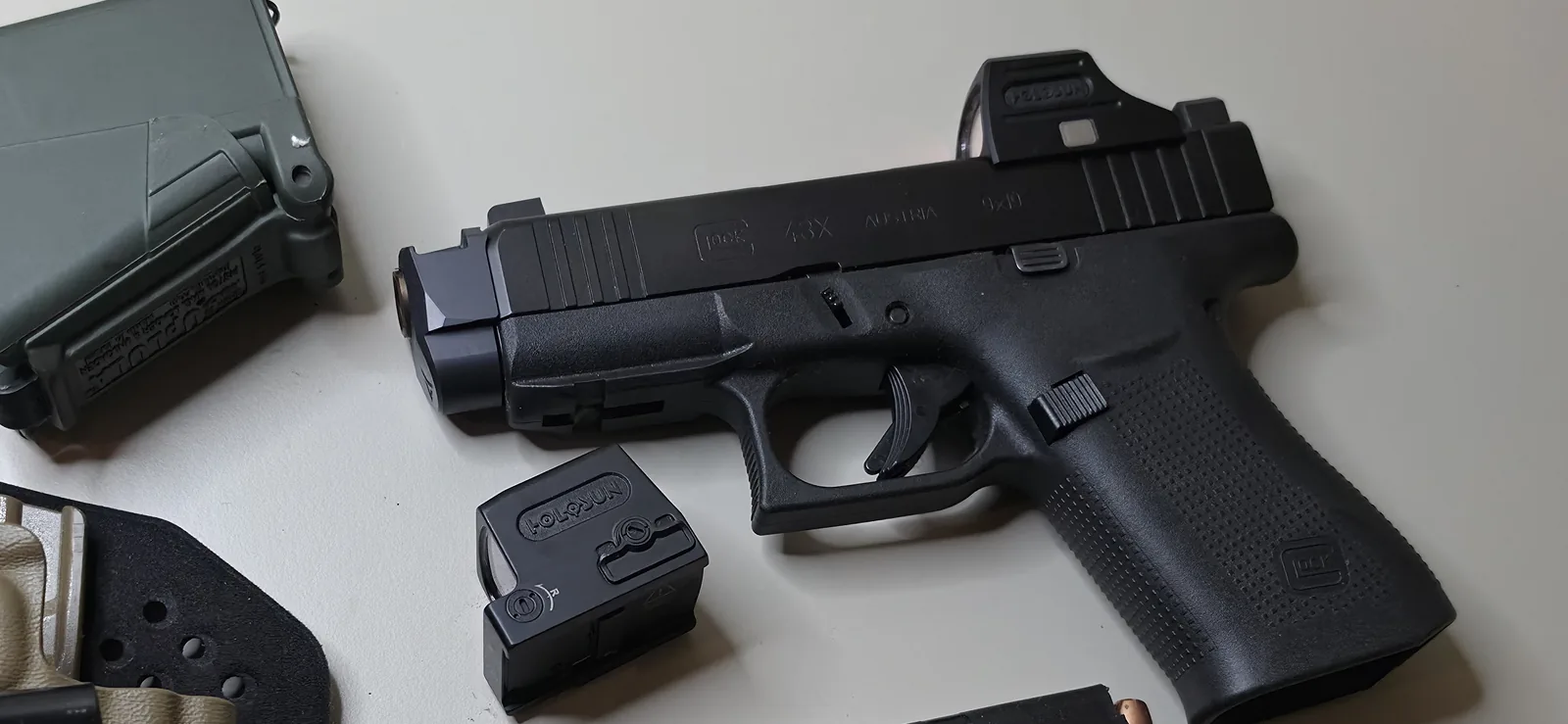 Glock 43X with a Radian Ramjet barrel and Afterburner compensator standing past the front of the slide and a Holosun red dot mounted