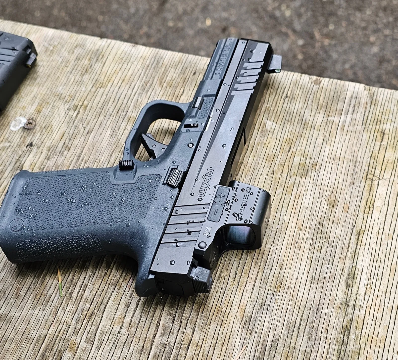 Ruger RXM on wood surface with water droplets beaded across the slide and frame after shooting in the rain