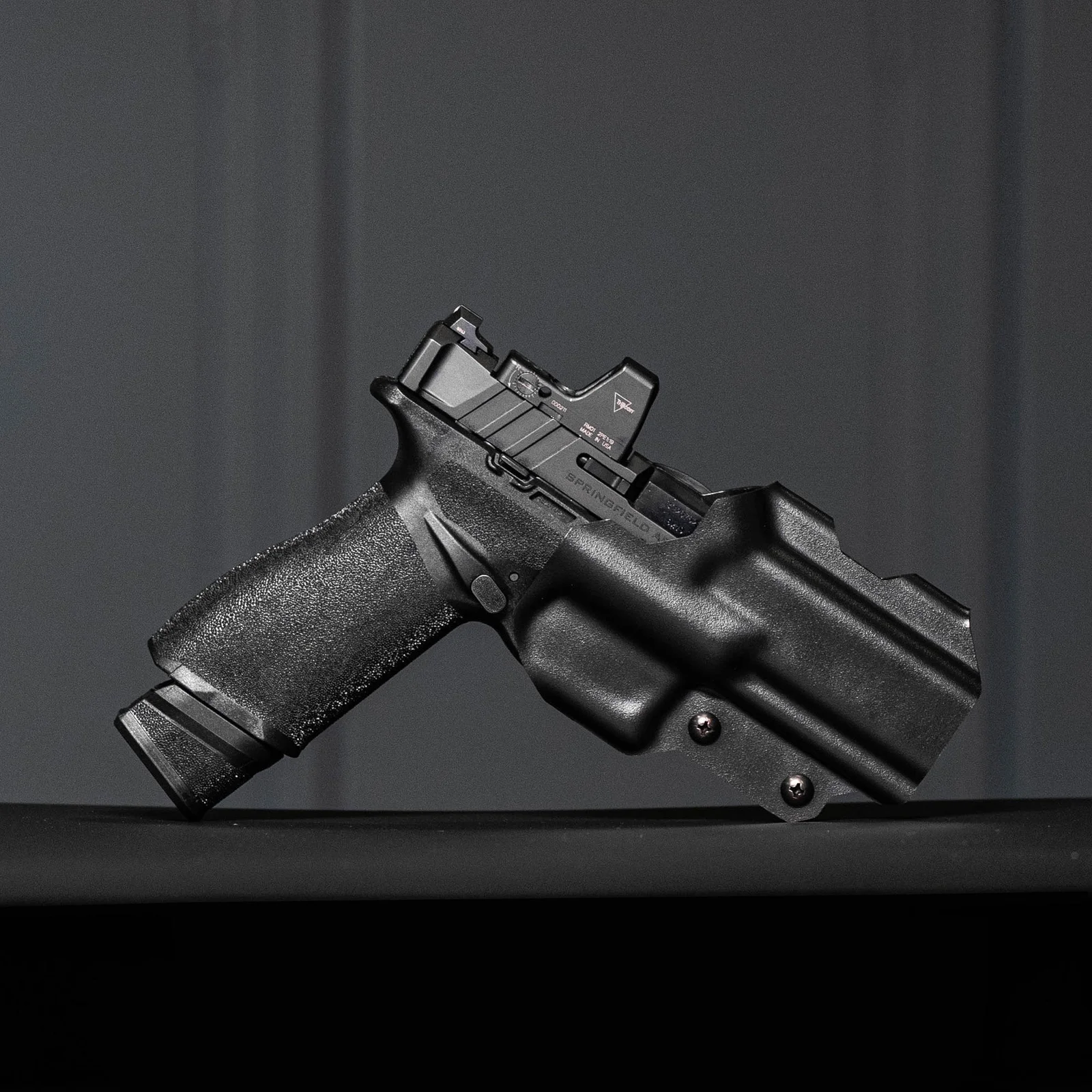 Springfield Echelon with red dot optic seated in a Blade-Tech Kydex holster against a dark studio background