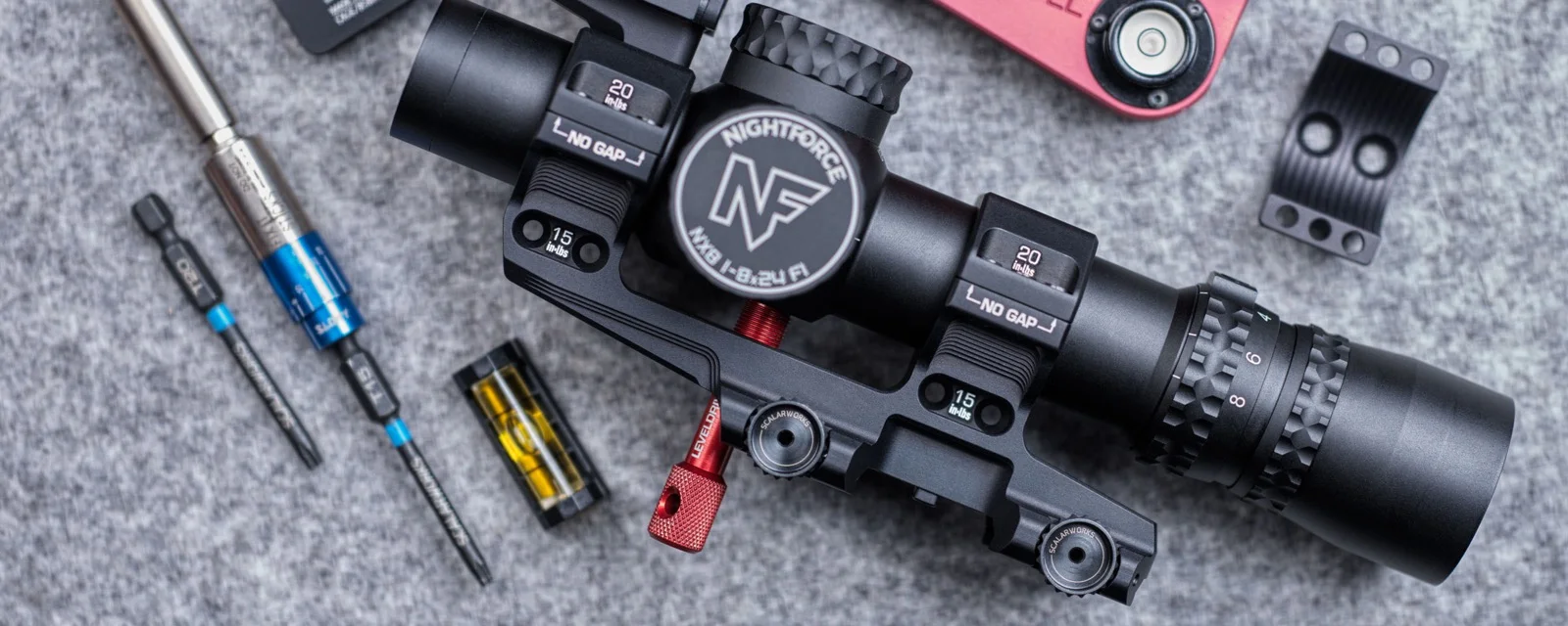 Scalarworks LEAP/08 holding a Nightforce NX8 while a red LevelDrive tool contacts the flat base of the scope
