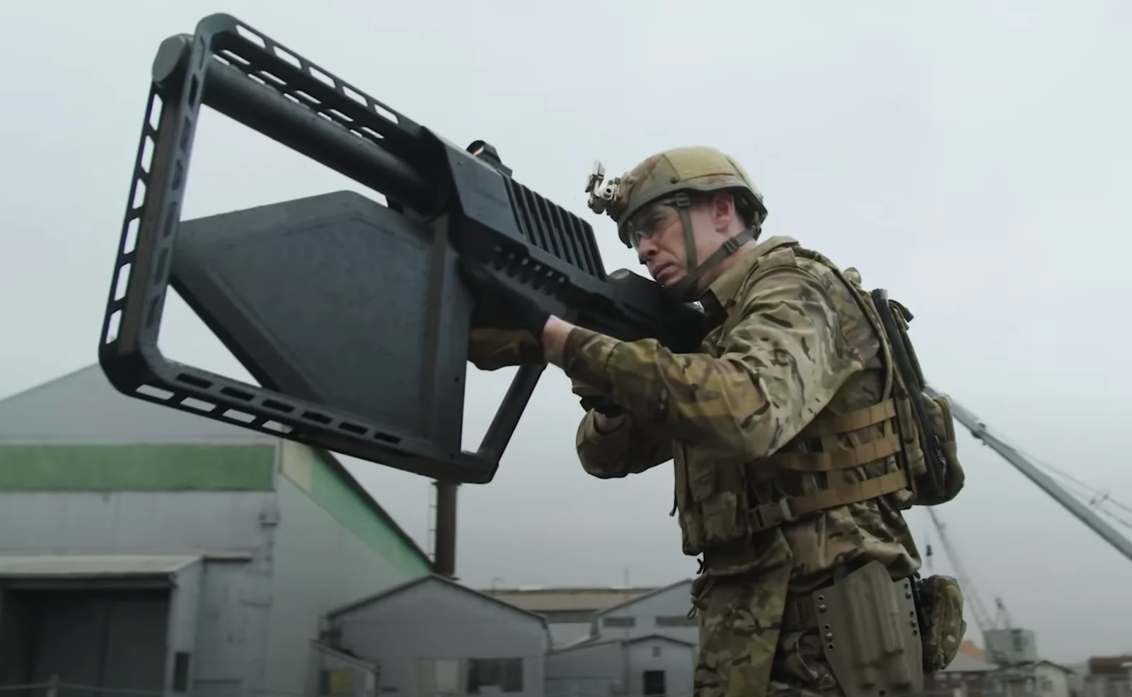 Uniformed service member shouldering a large handheld radio-frequency counter-drone jammer with a rectangular directional antenna array