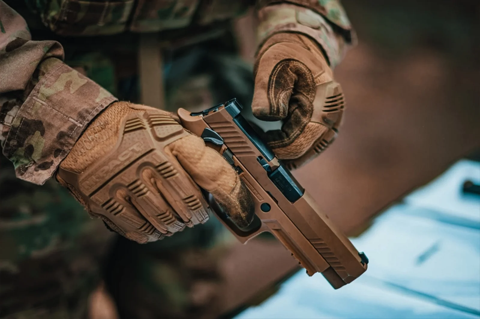 U.S. soldier in camouflage and tactical gloves holding a coyote tan SIG SAUER M17 service pistol