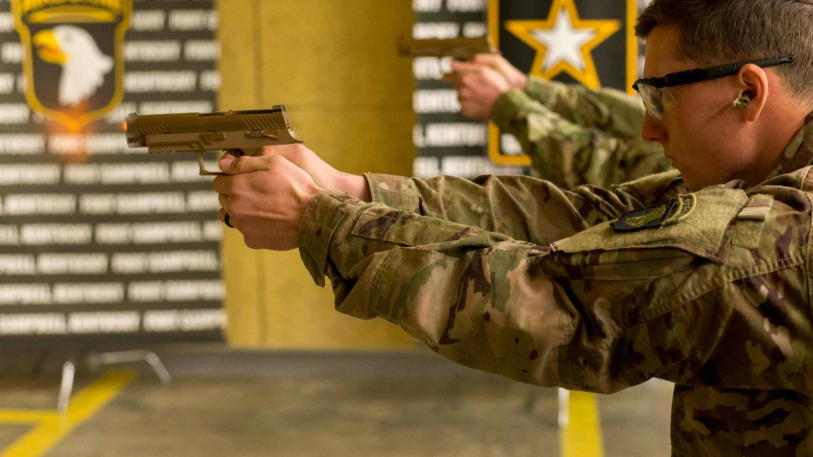 U.S. Army soldier aiming a SIG SAUER M17 service pistol at an indoor firing range