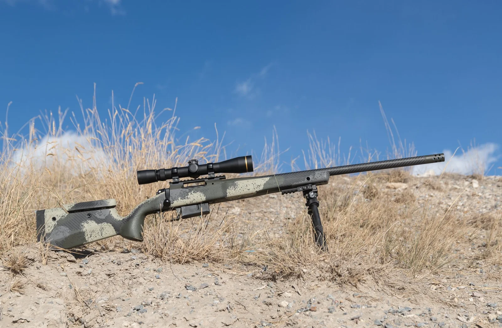 Springfield Model 2020 Waypoint with a hand-painted camo AG Composites stock and carbon fiber barrel resting on a bipod in dry grass