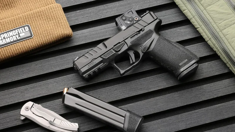Springfield Armory Echelon pistol with Aimpoint COA red dot sight on black textured surface with magazine and EDC accessories