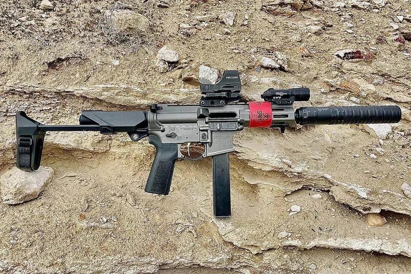 Springfield SAINT Victor 9mm PDW with a 9mm suppressor and red dot sight mounted, photographed in an outdoor range setting