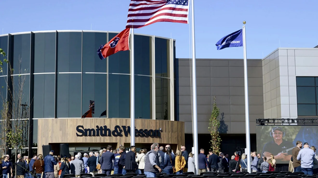 Smith & Wesson headquarters in Maryville, Tennessee, with a curved glass entrance, the Smith & Wesson name over the door, and flags flying above a crowd