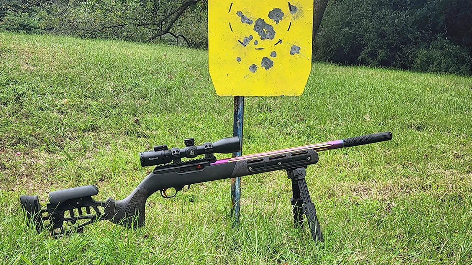 Custom 10/22 with a Taurus TTX22 suppressor on a bipod in front of a yellow steel plate