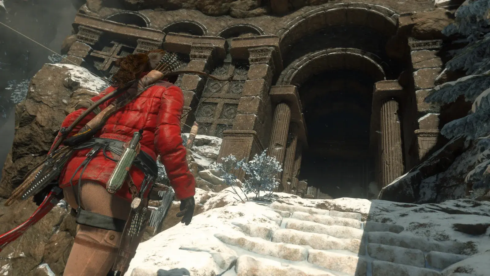 Lara Croft approaching a snowy ruin with a rifle and bow slung across her back
