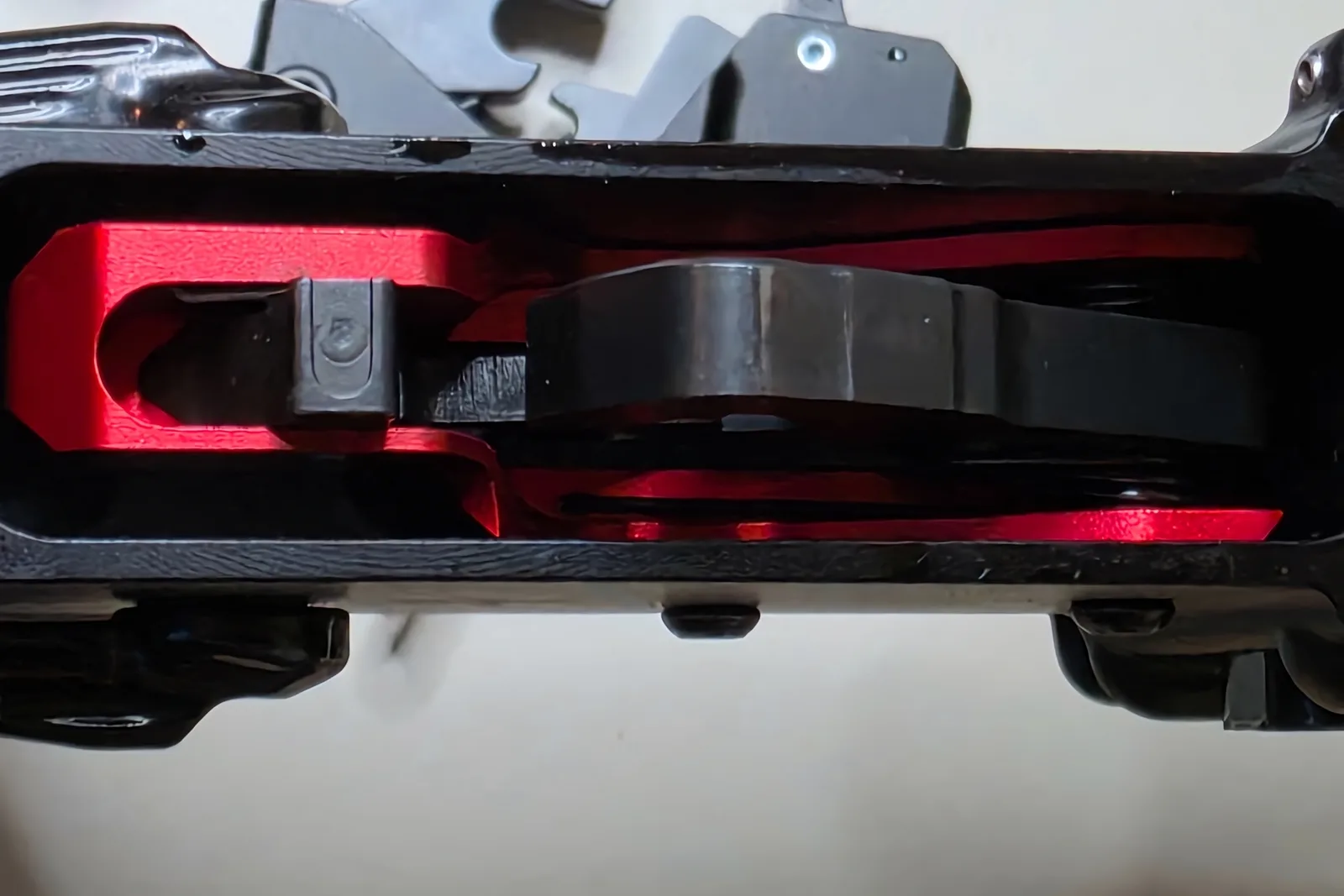 Top-down view into an AR-15 lower receiver's fire control pocket with a red Triggered Company LAT trigger cassette installed, hammer and housing visible