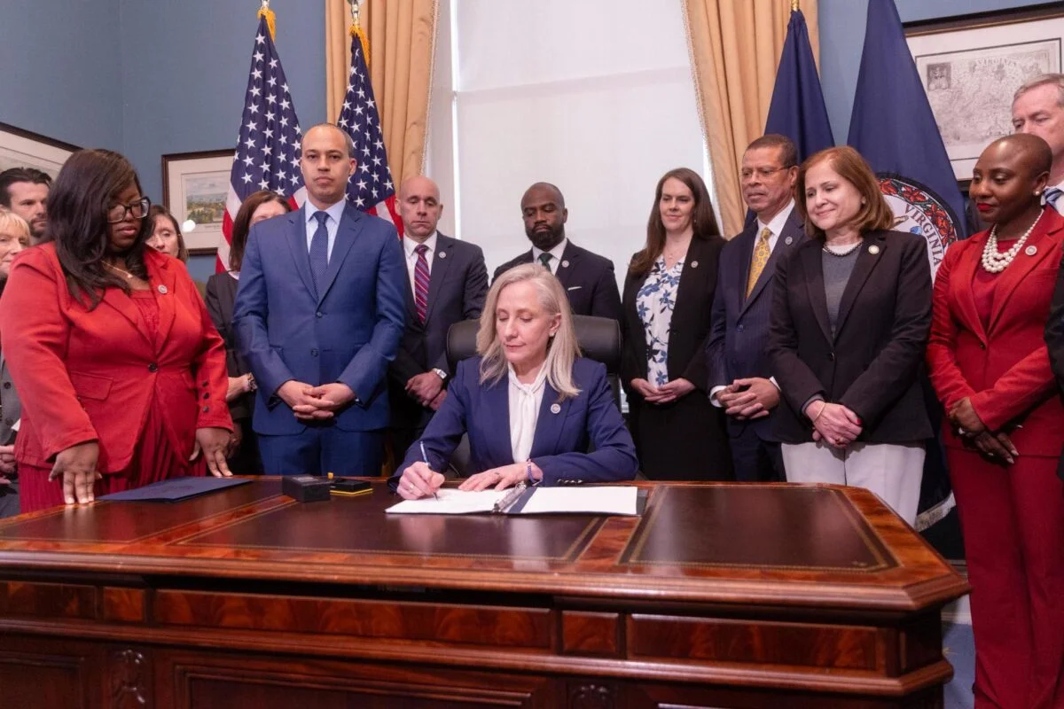 Virginia Governor Abigail Spanberger signing legislation at her desk in the State Capitol