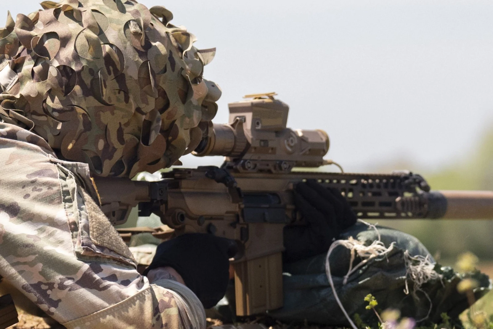 A 101st Airborne Division soldier in a ghillie cover fires an XM7 rifle fitted with the XM157 fire control during new equipment training at Fort Campbell