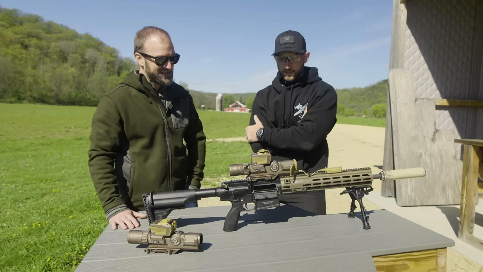 Hunter Constantine and a Vortex representative at a range bench with an HK MR762 A1 wearing the XM157 fire control and a second XM157 unit sitting on the table