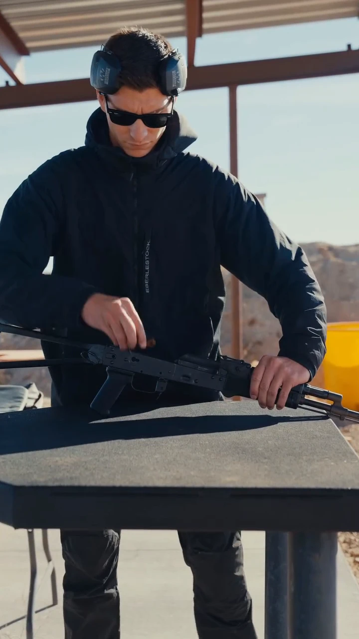 Shooter at a range bench installing The Wrangeler cassette into an open AK receiver