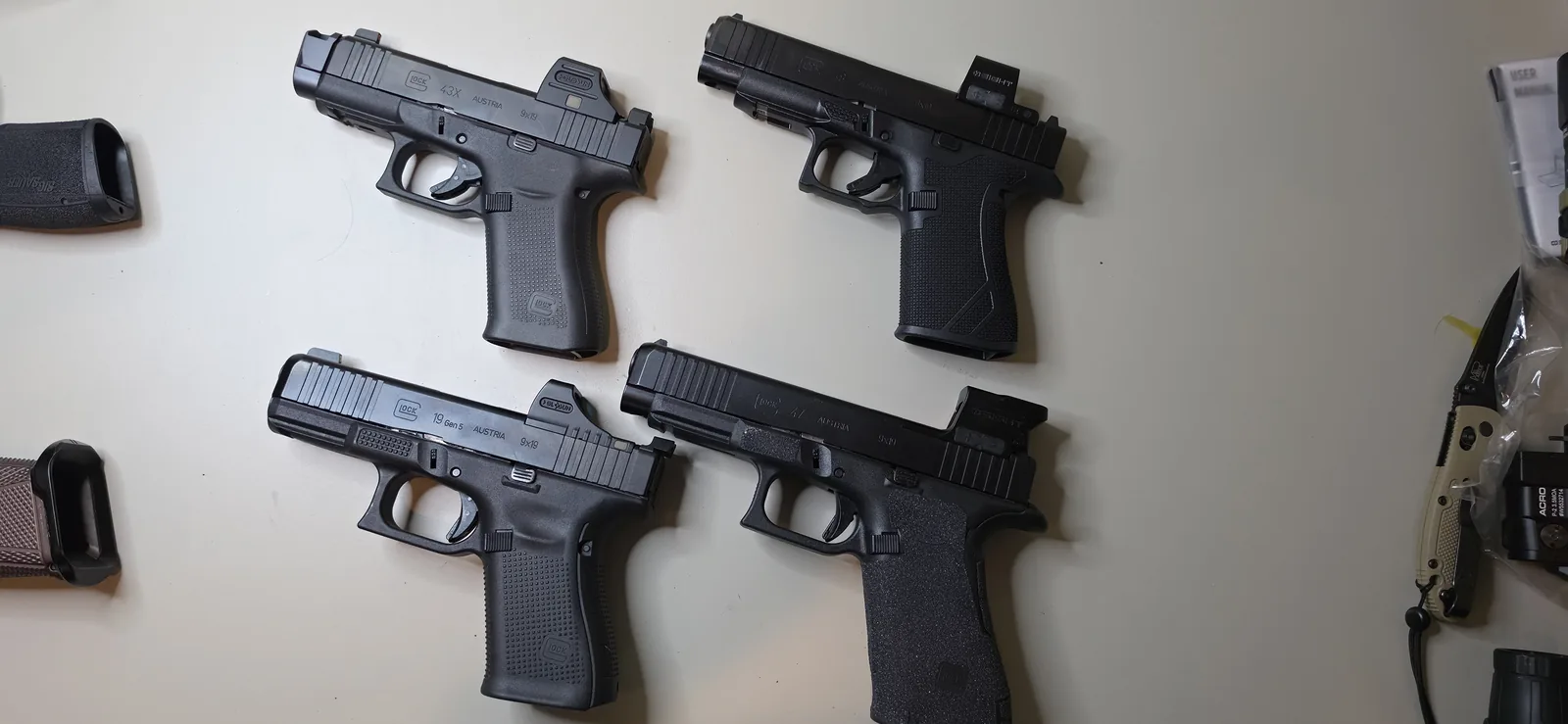 Four optic-ready 9mm Glock pistols laid out on a bench, a 43X and a 48 on the top row and a 19 Gen5 and a full-size 47 below