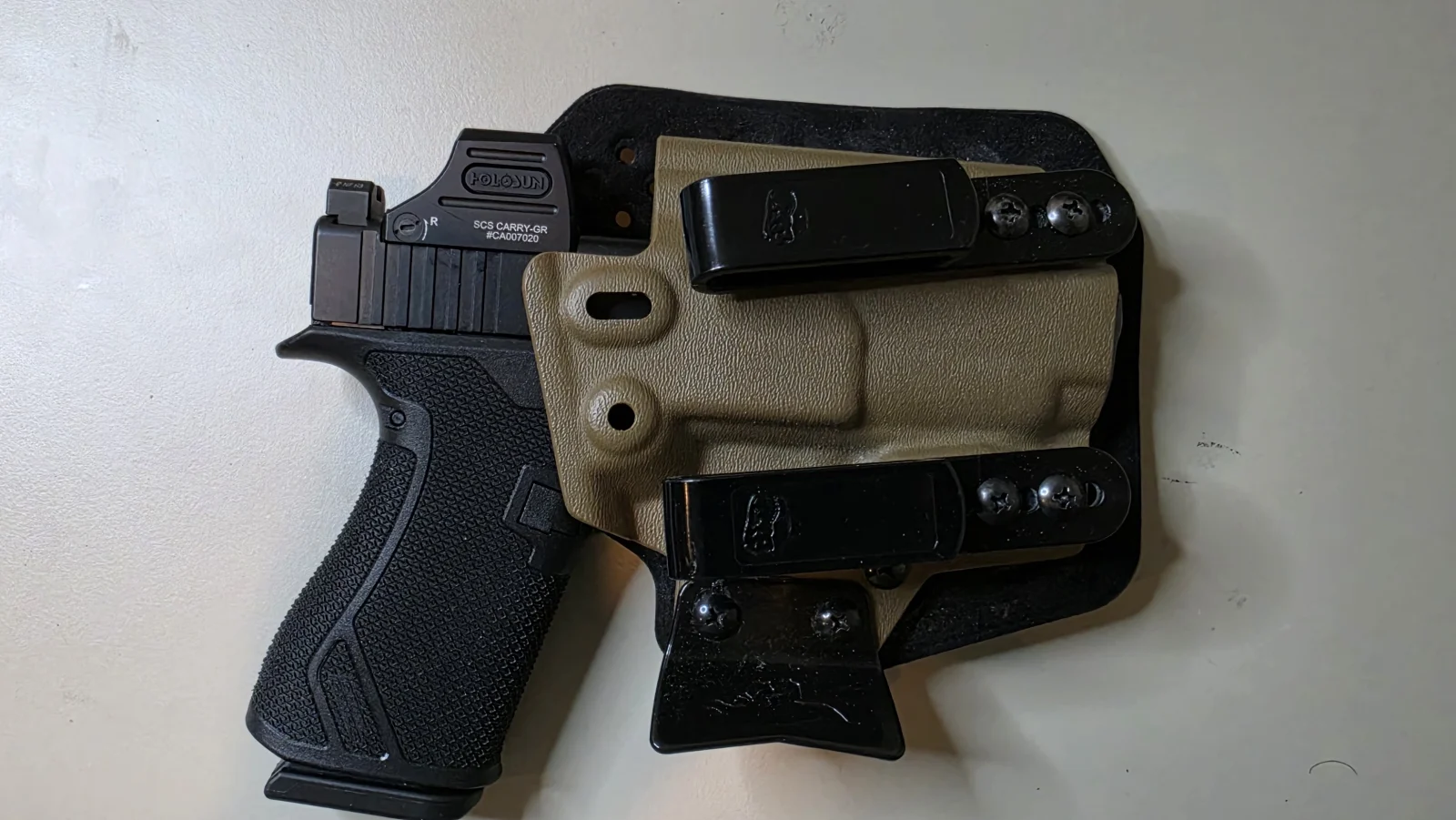 T.REX ARMS Ironside Hybrid holster with a coyote Kydex shell on a black soft backer, twin black tuckable belt clips and a black claw, laid beside a modified slimline Glock: a 43X upper on a Grit Grips frame with a Radian Ramjet barrel and a Holosun SCS Carry-GR enclosed green dot
