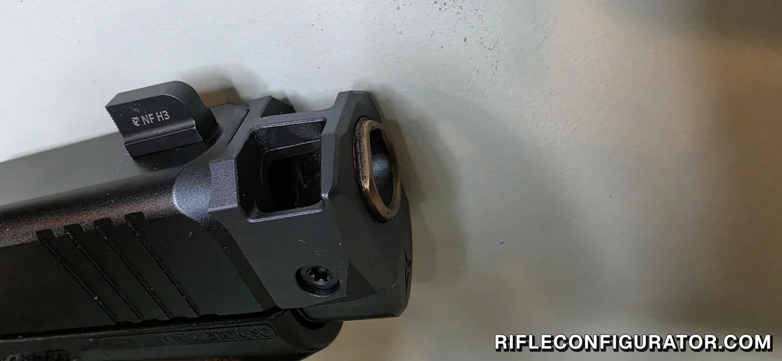 Close-up of an Agency Arms 417C compensator on a Glock 43X, with a Night Fision front sight seated in the comp body, a square top port ahead of it, and the barrel muzzle visible inside the comp