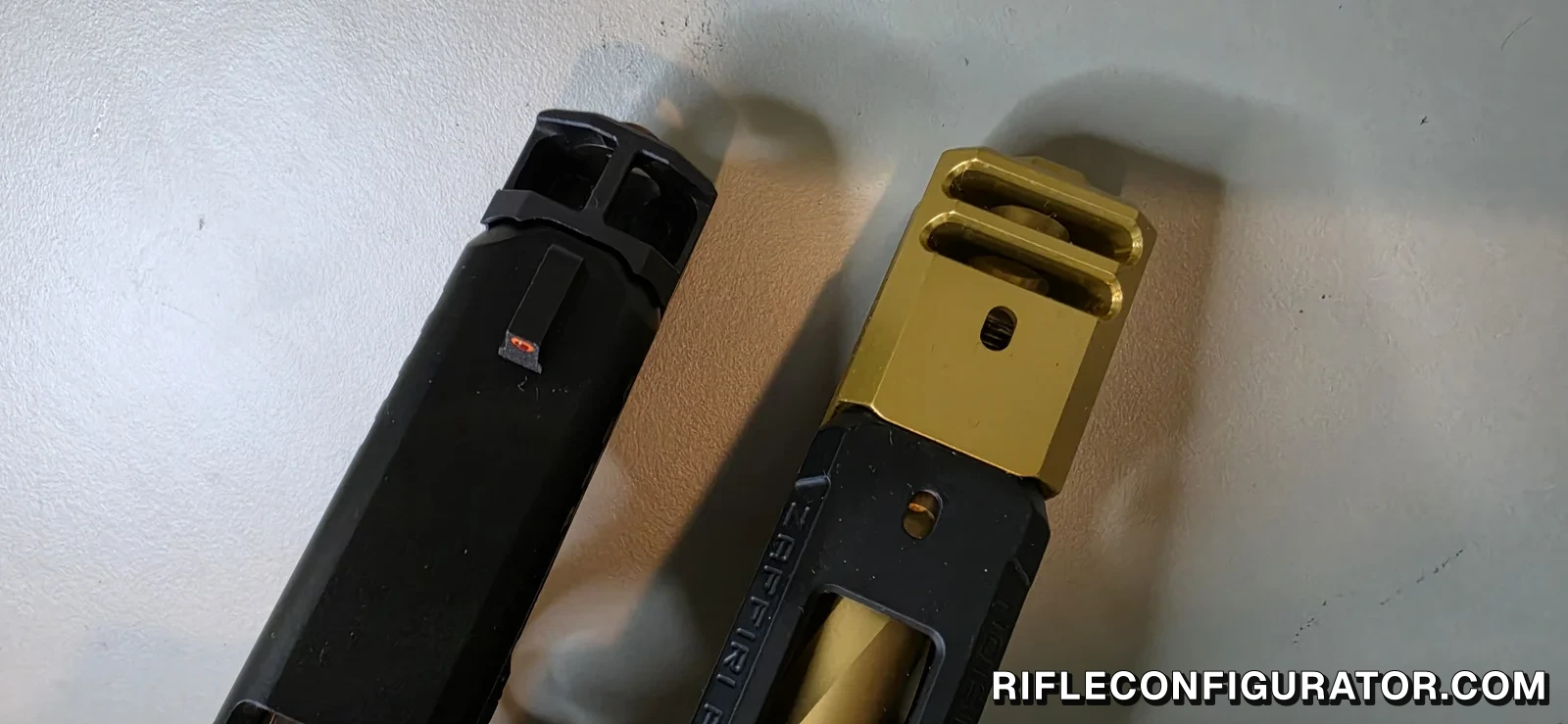 Two pistol compensators photographed from the muzzle end side by side, a black twin-port comp on a slimline Glock slide and a gold twin-port comp on a full-size Glock-pattern slide