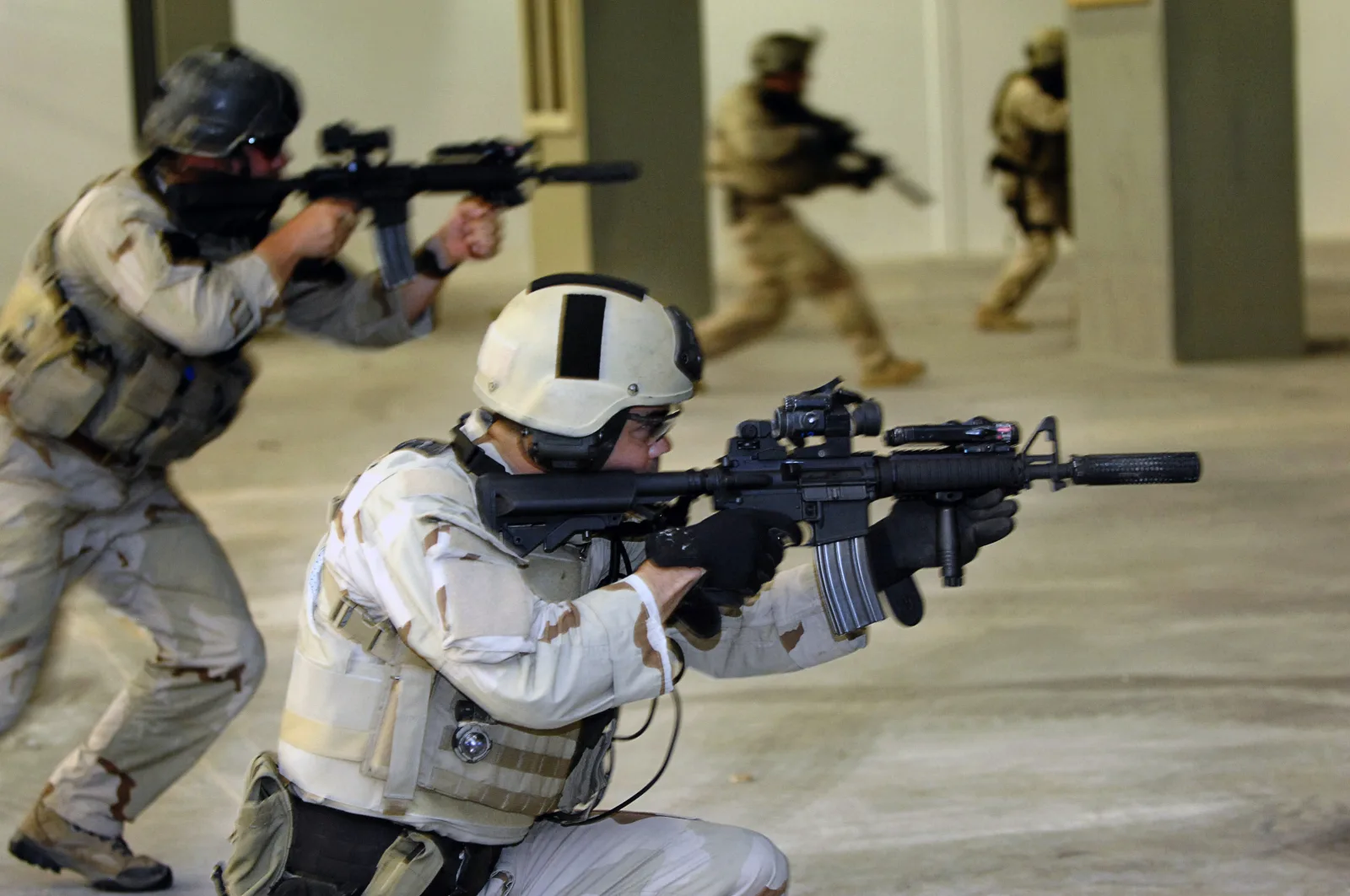 Navy SEALs clearing a shoot house with MK18 Mod 0 CQBR carbines fitted with KAC RAS quad rails, Aimpoint CompM2 optics, AN/PEQ-2 lasers, and KAC QD suppressors
