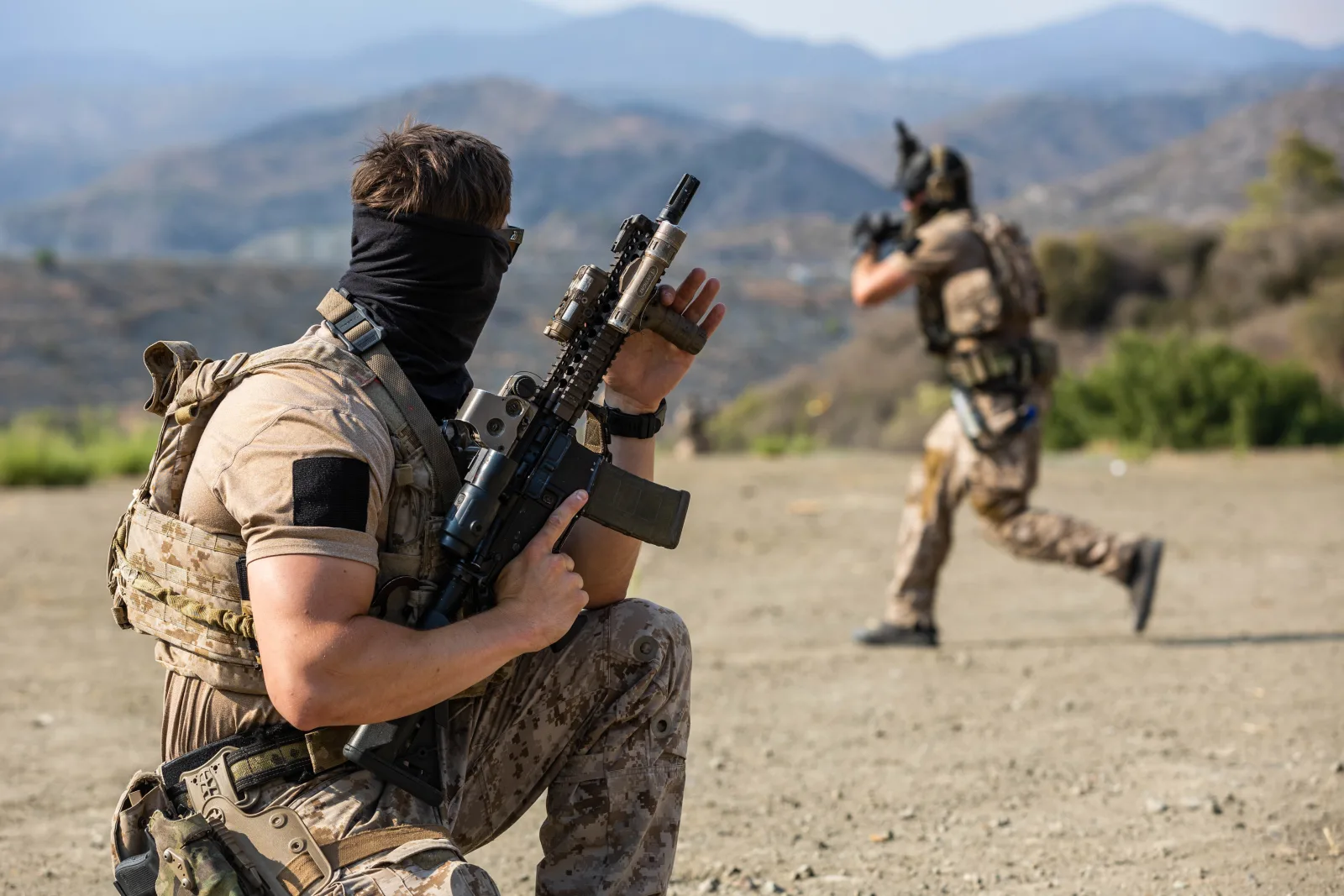 Naval Special Warfare operator kneeling with an MK18 Mod 1 with tan Daniel Defense RIS II quad rail, EOTech with flip-to-side magnifier, PEQ-15 laser, and SureFire Scout light