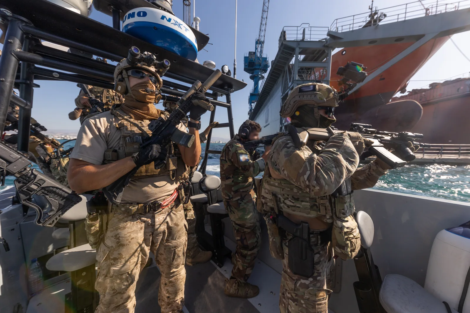 Naval Special Warfare operator on a boarding craft holding a suppressed MK18 Mod 1 with quad rail, SureFire Scout light, and PMAG during VBSS training